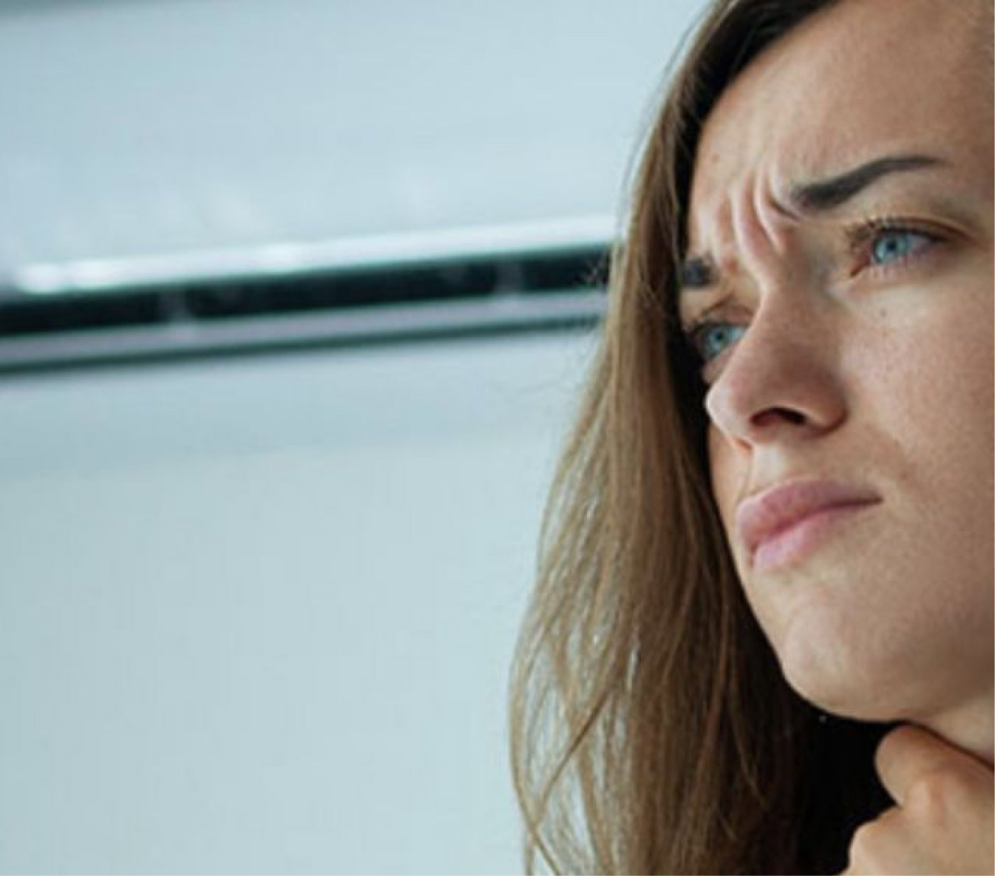 Una giovane donna con un malessere mette una mano sulla gola dolorante 